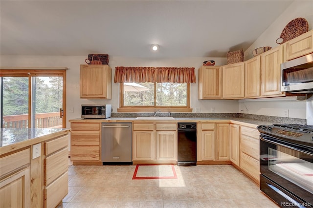 kitchen with light brown cabinetry, stainless steel appliances, lofted ceiling, and sink