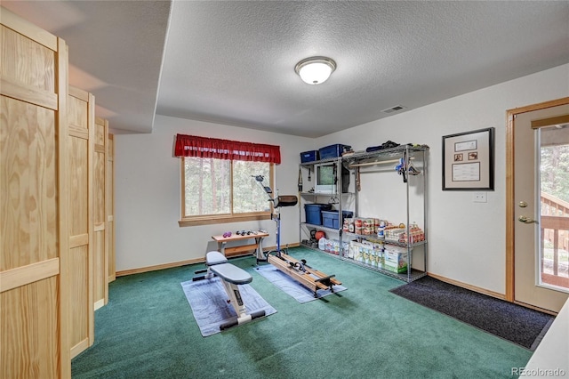 exercise area with dark carpet and a textured ceiling