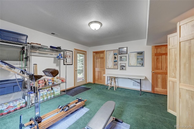 exercise area with dark carpet and a textured ceiling