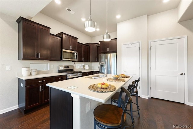 kitchen featuring sink, hanging light fixtures, a kitchen bar, a center island with sink, and appliances with stainless steel finishes