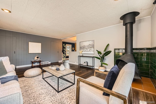 living room featuring wood finished floors, baseboards, and a wood stove