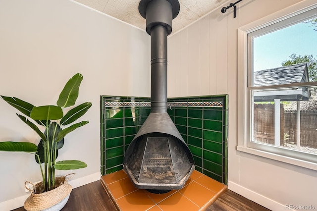 detailed view of wood finished floors, a wood stove, and baseboards