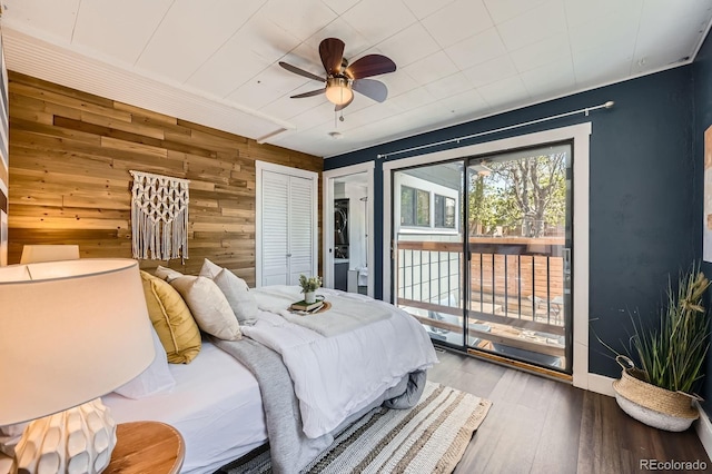 bedroom with access to outside, wooden walls, hardwood / wood-style floors, and ceiling fan