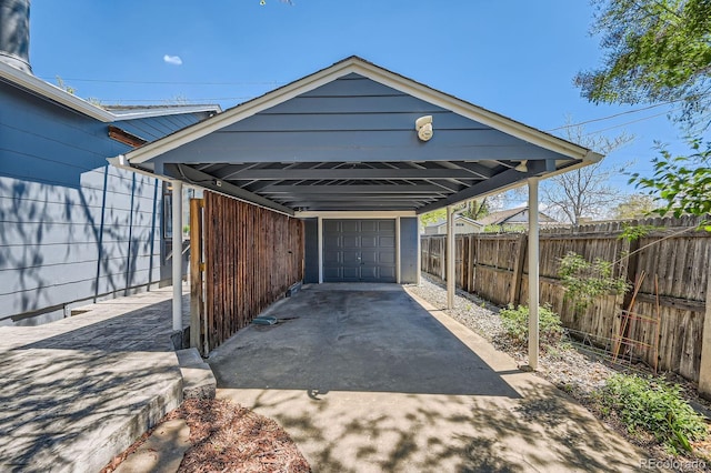 view of vehicle parking with fence and a detached garage