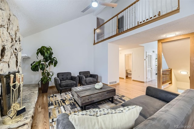 living room featuring visible vents, a ceiling fan, wood finished floors, a textured ceiling, and a fireplace