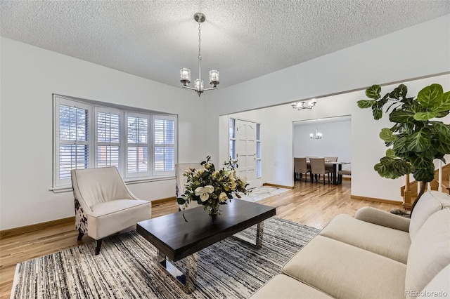 living room featuring a chandelier, light wood-type flooring, and a textured ceiling