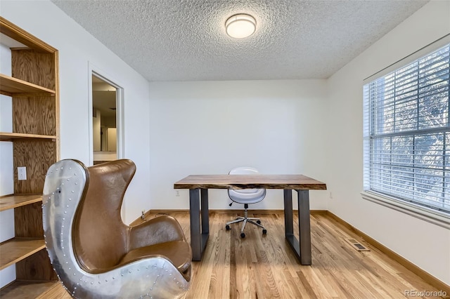 office area featuring visible vents, a textured ceiling, baseboards, and wood finished floors