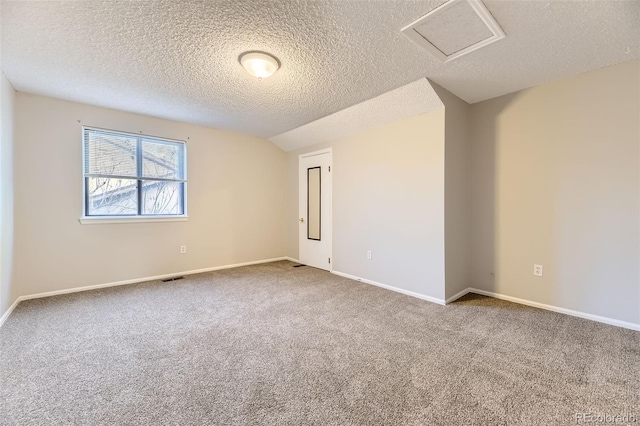 spare room with lofted ceiling, visible vents, attic access, carpet flooring, and baseboards