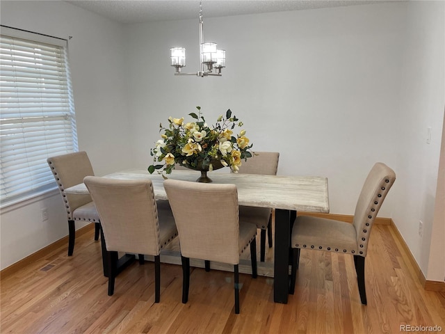 dining area featuring light wood-style floors, a wealth of natural light, baseboards, and an inviting chandelier