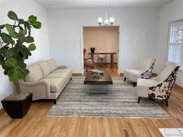 living room with a notable chandelier, a textured ceiling, and wood finished floors