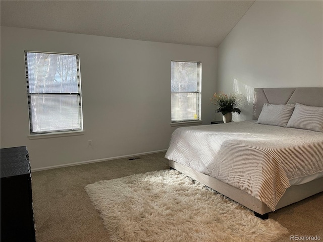 bedroom with vaulted ceiling, carpet flooring, visible vents, and baseboards