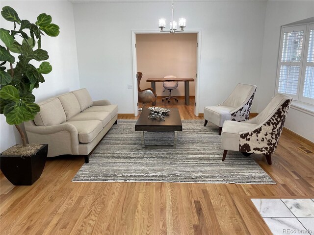 living room with baseboards, wood finished floors, and a notable chandelier