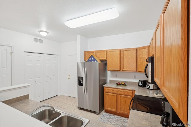 2502 S Bahama Cir Unit B, Aurora, CO 80013 - kitchen with stainless steel appliances, a sink, light tile patterned floors, light countertops, and brown cabinetry