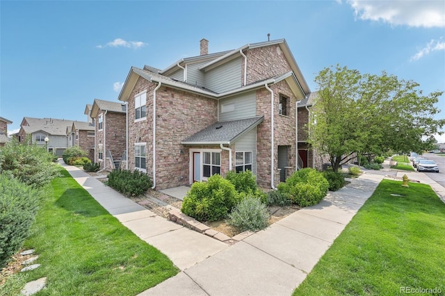 2502 S Bahama Cir Unit B, Aurora, CO 80013 - view of side of home with stone siding, a lawn, and a chimney