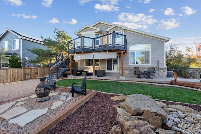 back of property with an outdoor living space with a fire pit, a patio, stairway, fence, and stone siding