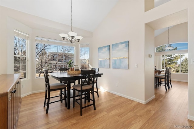 dining area featuring high vaulted ceiling, baseboards, light wood finished floors, and an inviting chandelier