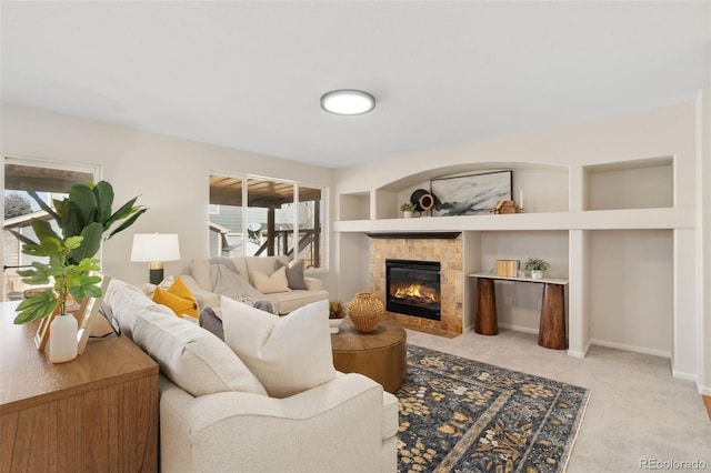 living area with built in shelves, light carpet, a fireplace, and baseboards