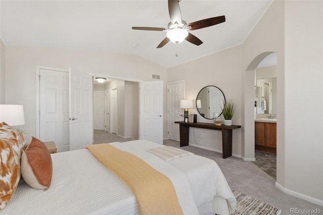 bedroom with arched walkways, light carpet, a sink, visible vents, and vaulted ceiling