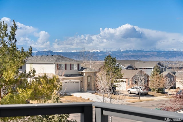 view of front facade with a balcony, a mountain view, a garage, concrete driveway, and a residential view