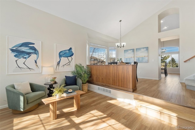 sitting room with a chandelier, high vaulted ceiling, visible vents, light wood-style floors, and stairway