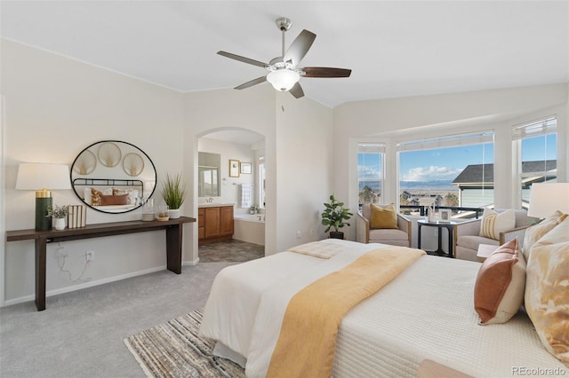 bedroom featuring light carpet, baseboards, arched walkways, a ceiling fan, and vaulted ceiling