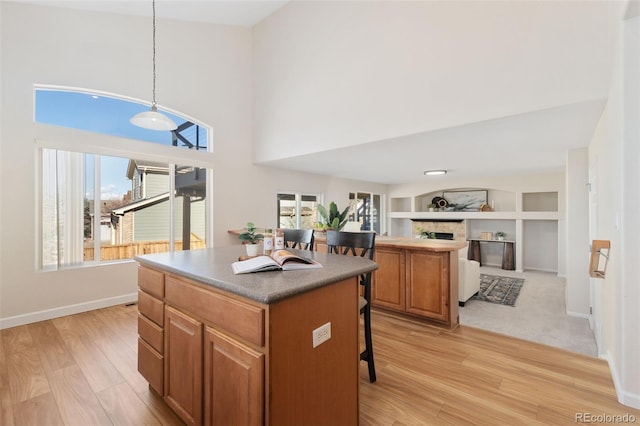 kitchen featuring brown cabinets, open floor plan, a center island, a fireplace, and pendant lighting