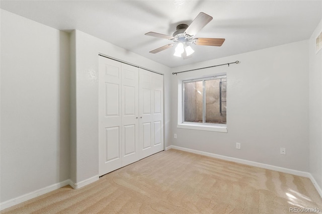 unfurnished bedroom with a ceiling fan, a closet, light carpet, and baseboards