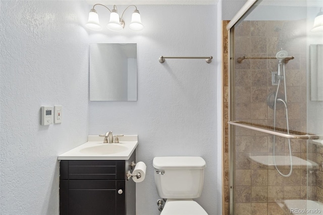 bathroom featuring toilet, a stall shower, and vanity