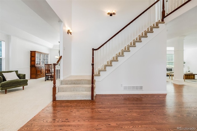 stairs featuring hardwood / wood-style flooring and a towering ceiling