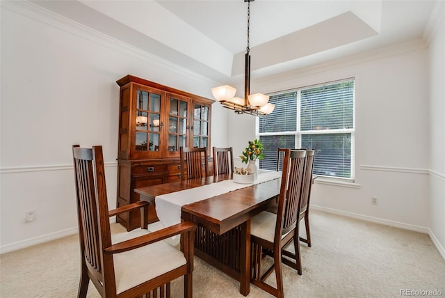 carpeted dining space featuring crown molding, a raised ceiling, and a chandelier