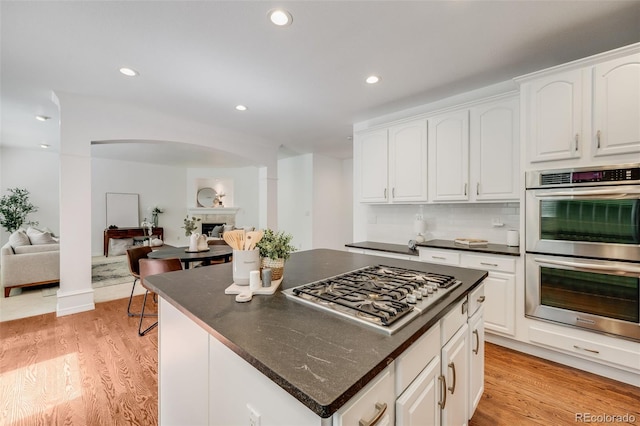 kitchen with white cabinetry, stainless steel appliances, tasteful backsplash, and light wood-type flooring