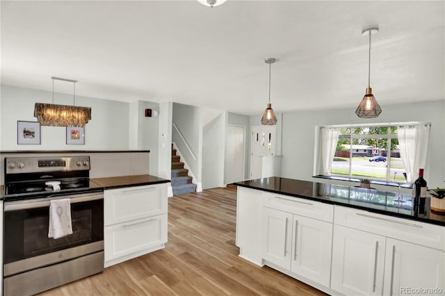 400 S Hoyt St, Lakewood, CO 80226 - kitchen with stainless steel electric range, dark countertops, light wood-style floors, white cabinets, and pendant lighting