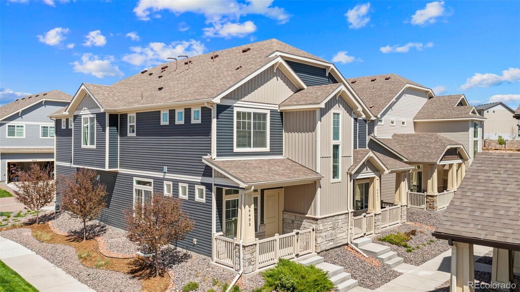 6405 Glencullen Vw, Colorado Springs, CO 80927 - view of side of property featuring stone siding, a shingled roof, a residential view, and covered porch