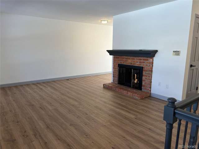 unfurnished living room featuring hardwood / wood-style floors and a brick fireplace