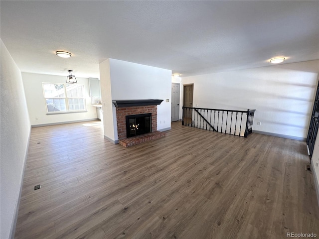 unfurnished living room with a brick fireplace and dark hardwood / wood-style floors