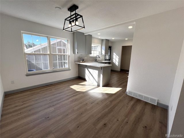 kitchen with sink, a breakfast bar area, hanging light fixtures, kitchen peninsula, and backsplash