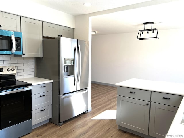 kitchen featuring gray cabinetry, decorative backsplash, hardwood / wood-style flooring, and appliances with stainless steel finishes