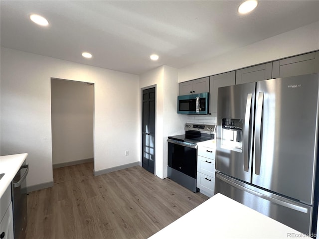 kitchen featuring appliances with stainless steel finishes, gray cabinetry, backsplash, and light hardwood / wood-style flooring