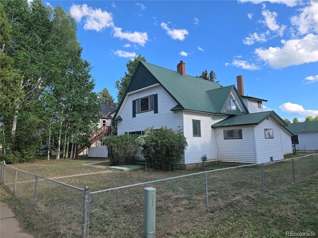 104 Joe S Chavez Dr, La Jara, CO 81140 - view of home's exterior featuring a chimney, a fenced backyard, and a metal roof