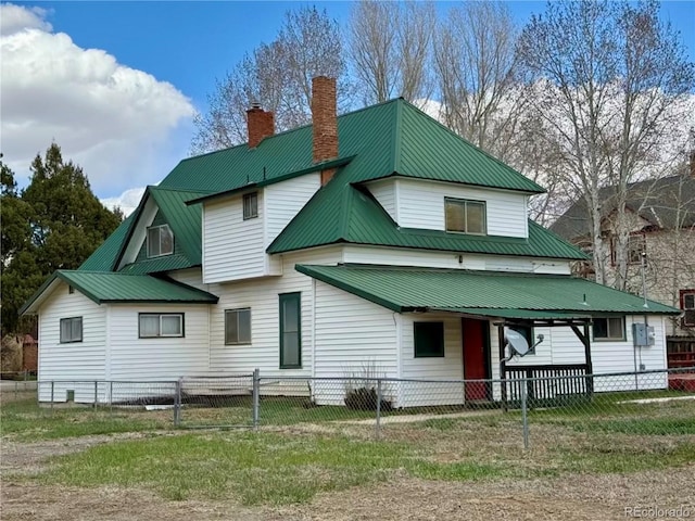 104 Joe S Chavez Dr, La Jara, CO 81140 - back of house with a metal roof, a chimney, a fenced front yard, and covered porch