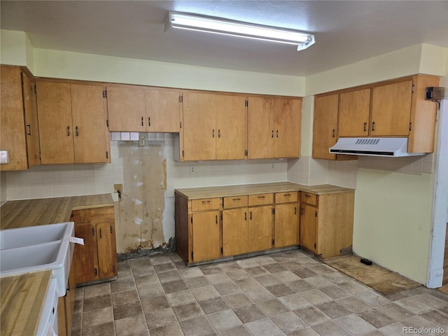 104 Joe S Chavez Dr, La Jara, CO 81140 - kitchen with exhaust hood, decorative backsplash, stone finish flooring, and brown cabinetry