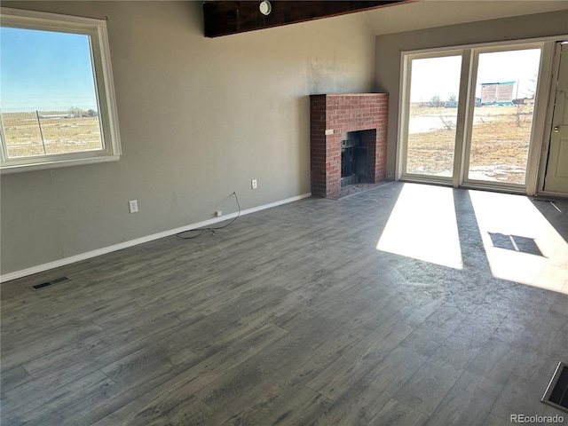 unfurnished living room with vaulted ceiling, a brick fireplace, and dark hardwood / wood-style floors