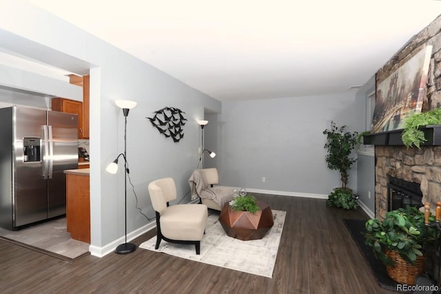 sitting room featuring a stone fireplace and dark hardwood / wood-style flooring