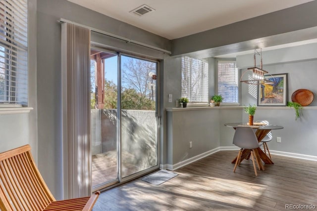 doorway to outside with a wealth of natural light, hardwood / wood-style floors, and a chandelier