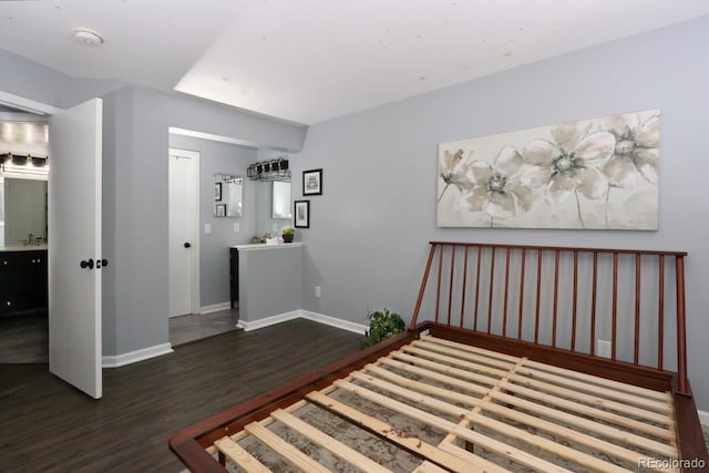 bedroom with dark hardwood / wood-style floors, sink, and ensuite bath