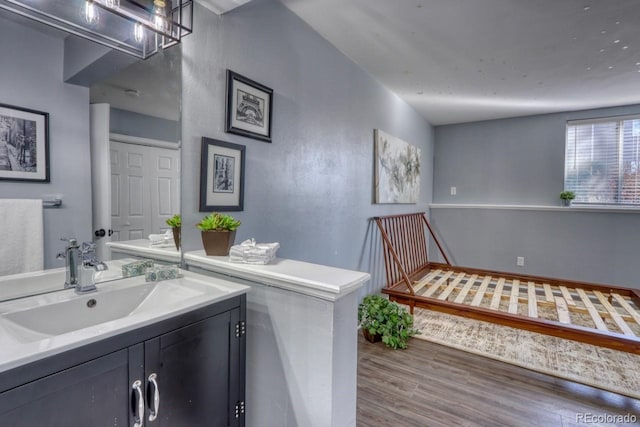 bathroom featuring hardwood / wood-style flooring, vanity, and lofted ceiling