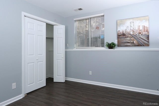 unfurnished bedroom with a closet and dark wood-type flooring