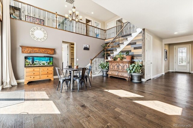 dining area featuring wood-type flooring, a high ceiling, and an inviting chandelier