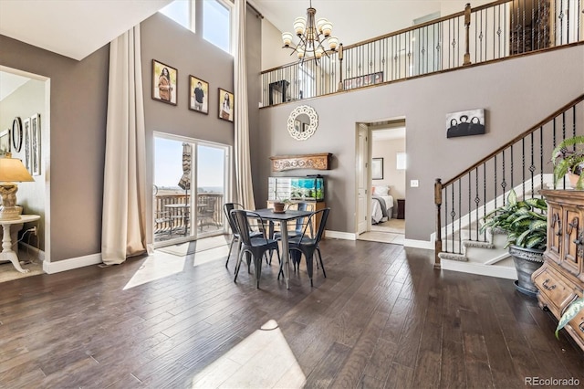 dining area with hardwood / wood-style flooring, a high ceiling, and an inviting chandelier