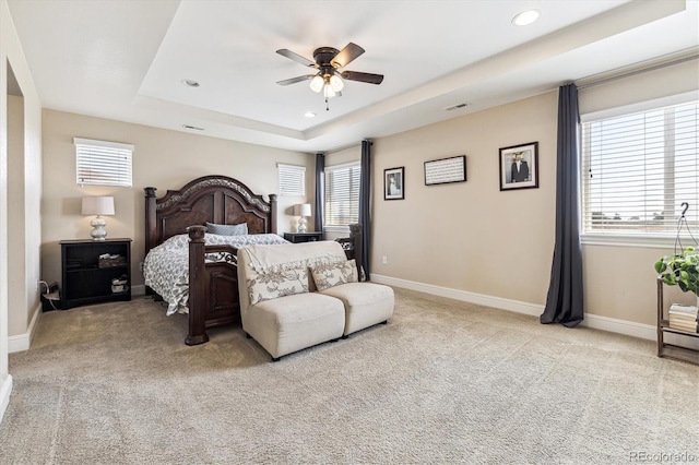 bedroom featuring light carpet, ceiling fan, and a tray ceiling